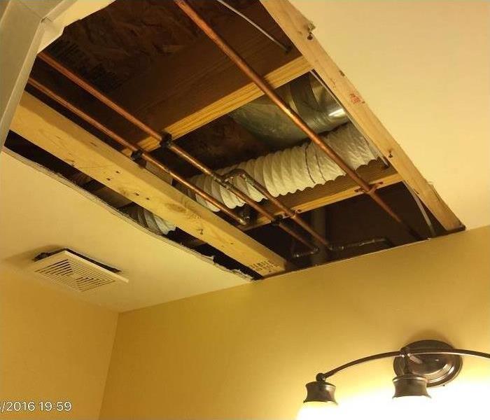 cut away damaged ceiling revealing the copper pipes and flex a/c ductwork