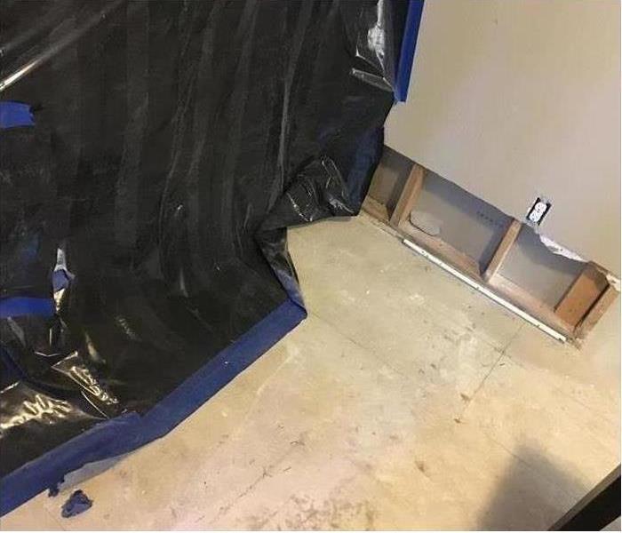 black containment barrier (a sheet of plastic) and cleaned wall ready to reinstall drywall