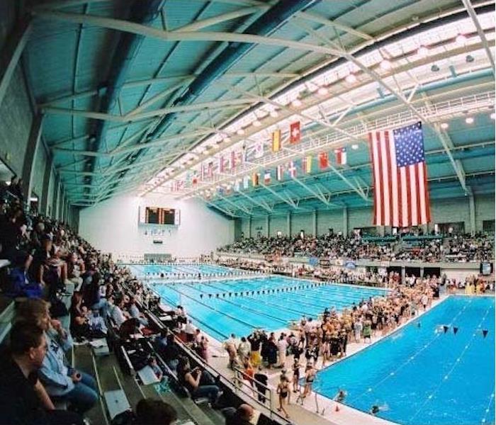 Swimming pools with people sitting in the stands and standing next to the pool