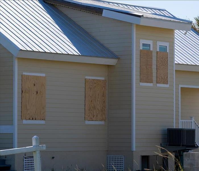 Hurricane shutters made from plywood mounted for protection of house windows.