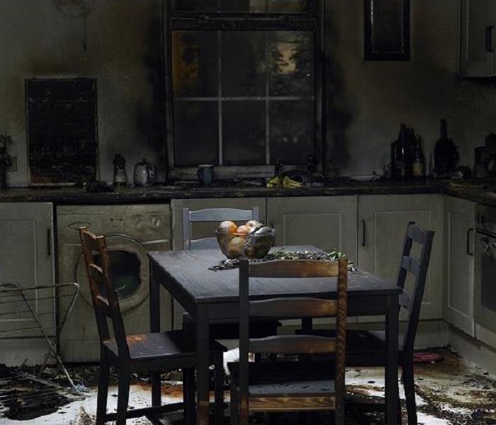 Aftermath of kitchen fire shown; smoke and soot on everything; table and chairs in middle of room